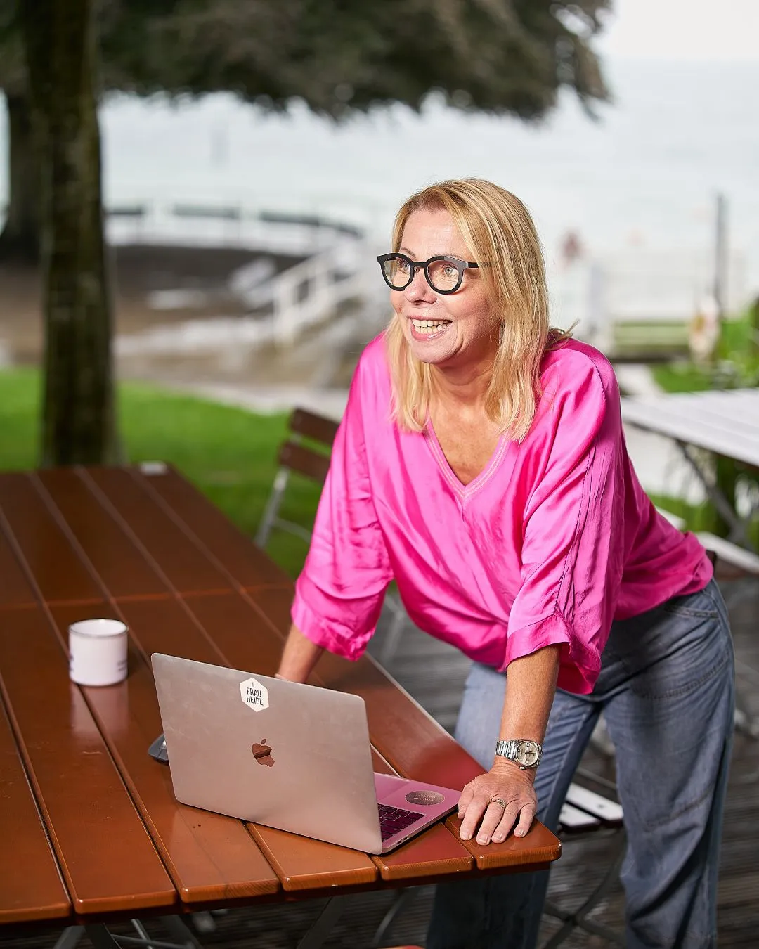 frauheide® steht draussen mit ihrem Laptop auf dem Biergartentisch uns hört zu. Das Wetter ist regnerrisch. Perfekt, um sich aufzuschlauen.